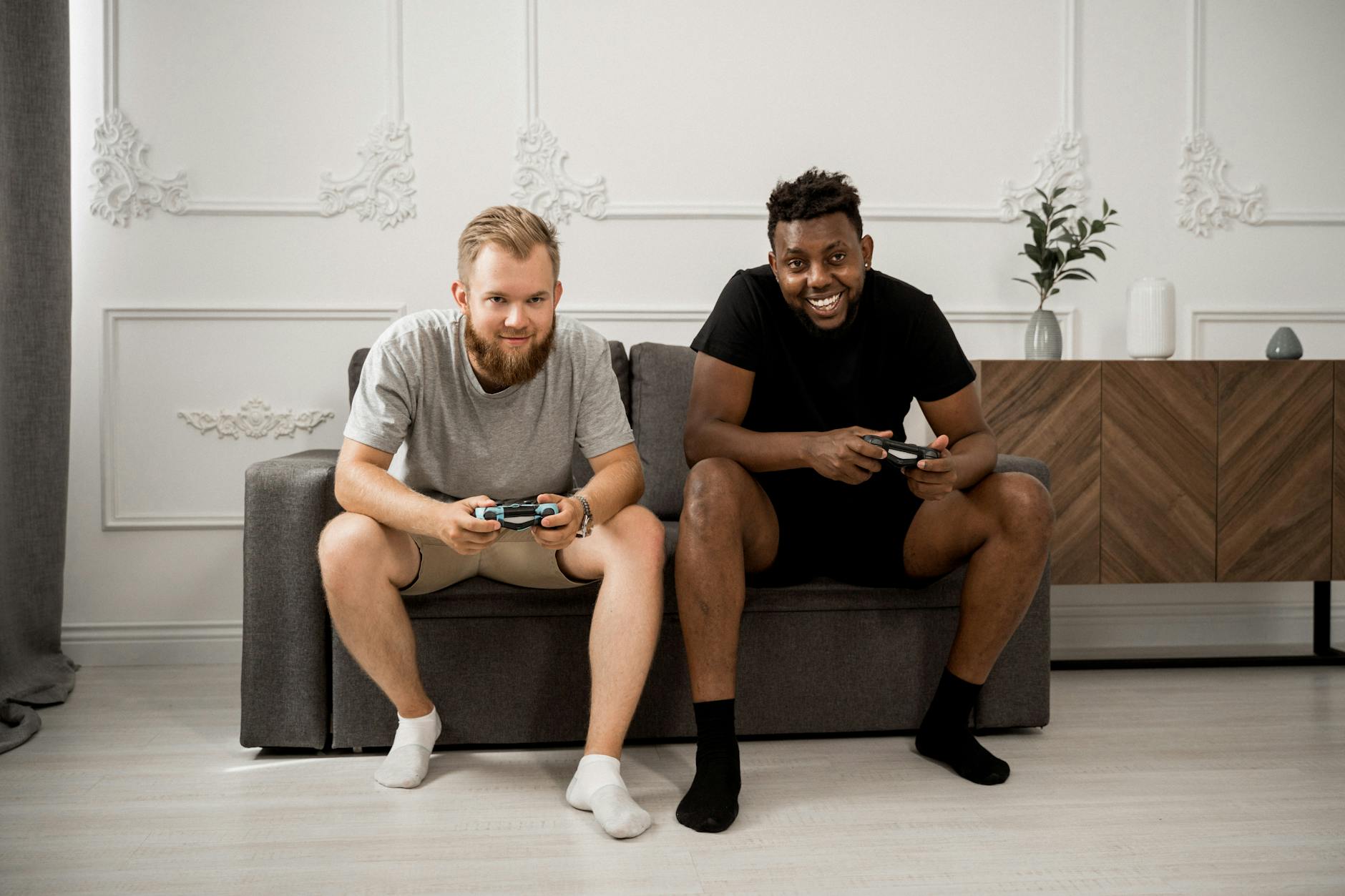 Dwóch mężczyzn gra razem w gry wideo na kanapie w salonie