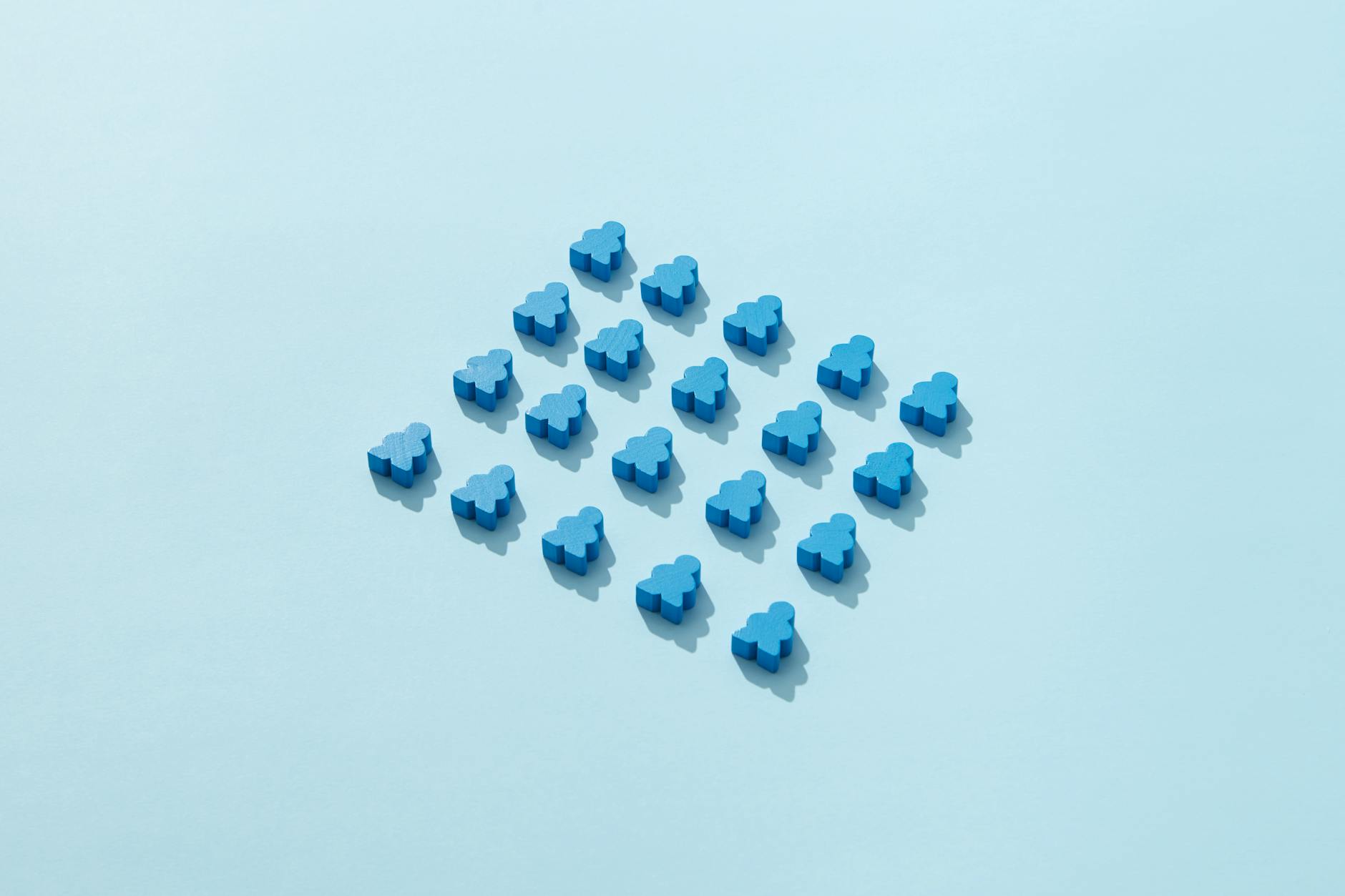 Niebieskie pionki meeple ułożone na jasnoniebieskim tle