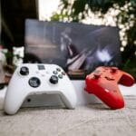 Biały i czerwony bezprzewodowy kontroler Xbox na tle monitora
