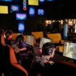Grupa graczy online przy komputerach w nowoczesnej kawiarni internetowej
