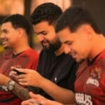 Trzech młodych graczy skupionych na mobilnych rozgrywkach e-sportowych