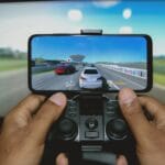 Dłonie grające w mobilną grę na smartfonie z podłączonym kontrolerem