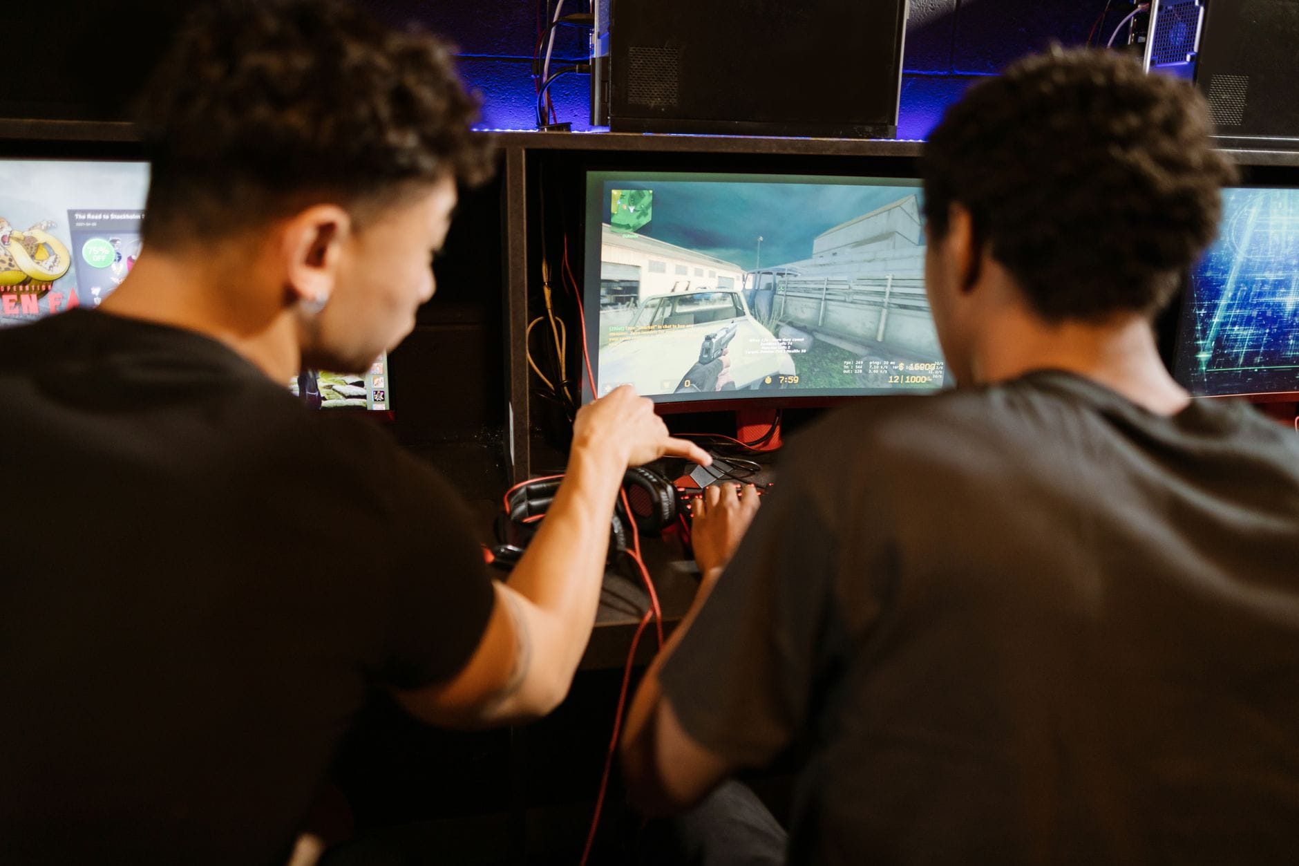 Dwóch młodych mężczyzn gra w arcade’ową grę MMO na automatach