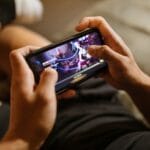 Gracz trzyma smartfon i gra w mobilne MMO