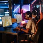 Gracze przy komputerach w neonowym świetle podczas rozgrywki MMO