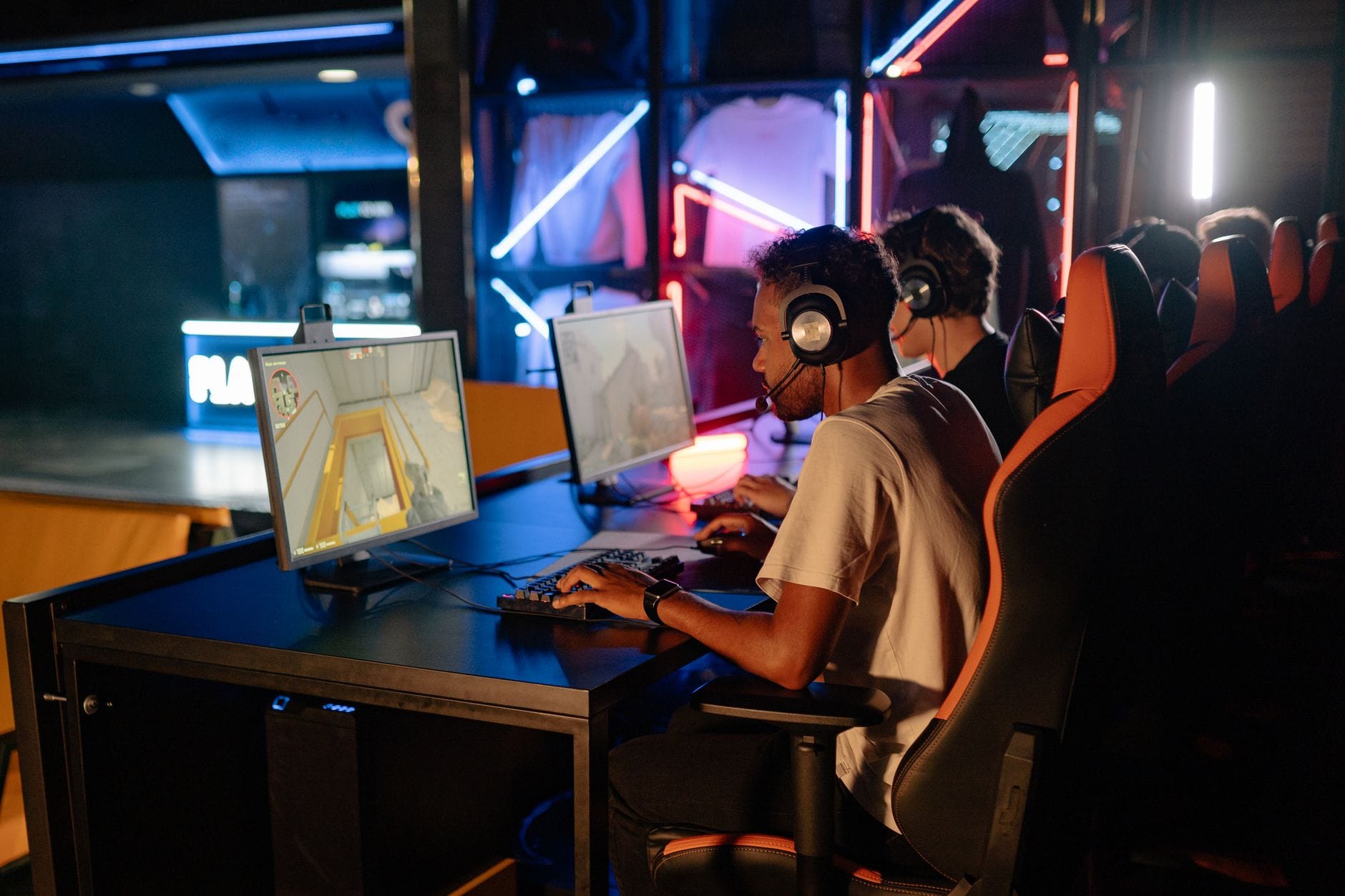 Gracze przy komputerach w neonowym świetle podczas rozgrywki MMO
