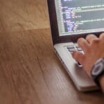 Programista piszący kod na laptopie podczas pracy nad aplikacją Java