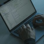 Programista pisze kod na laptopie, ekran z narzędziami bezpieczeństwa