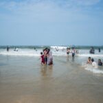 Rodziny z dziećmi bawią się w falach na słonecznej plaży nad morzem