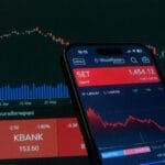 Smartfon z aplikacją giełdową i wykresami rynku na ekranie