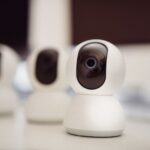 Trzy białe kamery do monitoringu IP stojące na biurku w domu
