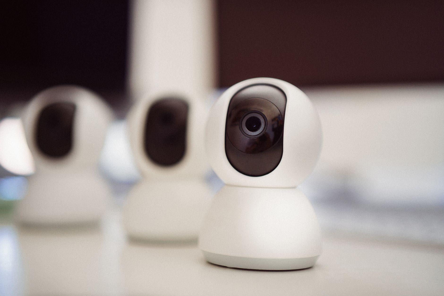 Trzy białe kamery do monitoringu IP stojące na biurku w domu