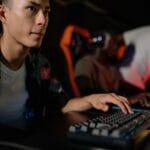 Młodzi gracze e-sportowi skupieni przy komputerach podczas turnieju